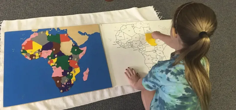 A child working with a puzzle map of Africa