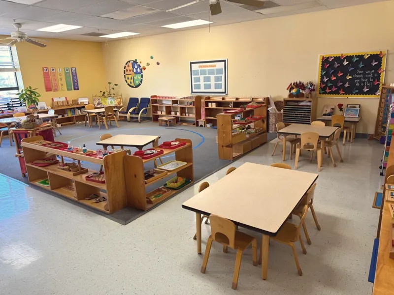 An Early Childhood classroom with work tables and shelves of Montessori materials
