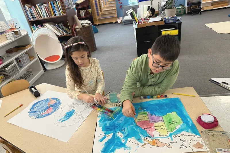 Two children painting a map together