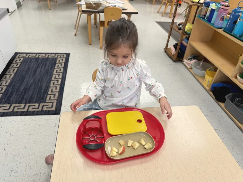 A toddler at a small table with a breakfast tray